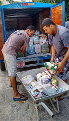 Foto de pessoas colocando alimentos na caçamba de uma caminhonete
