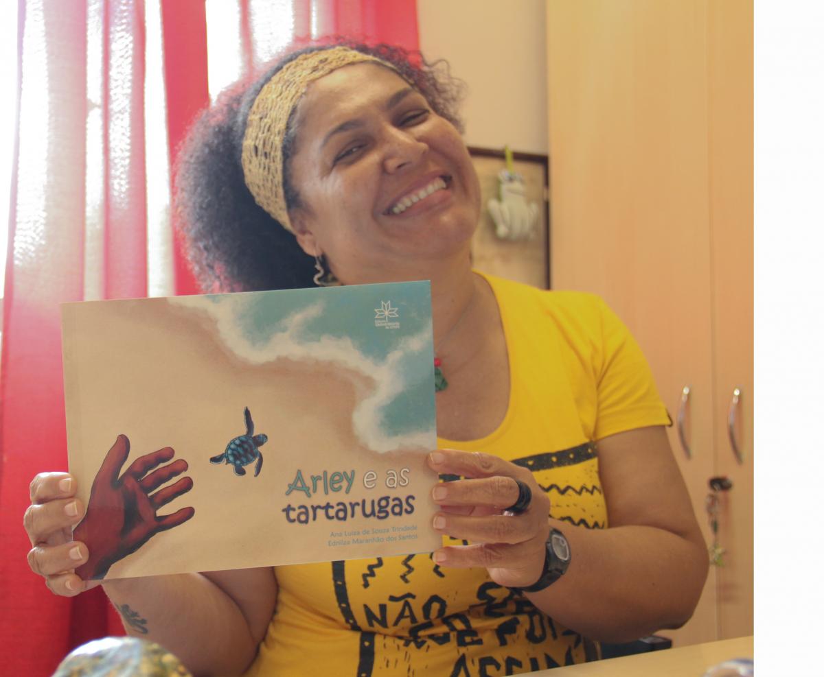 A professora Ednilza Maranhão segurando o livro Arley e as tartarugas